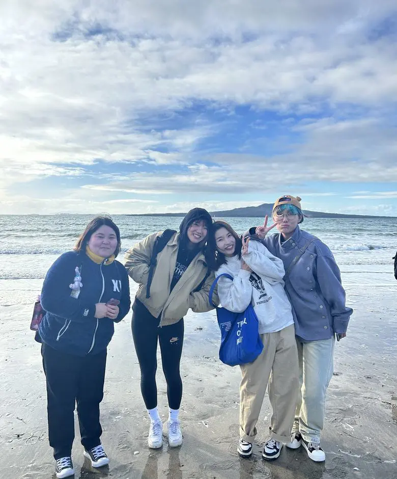 オークランドのビーチに立つ留学生4人。沖にはランギトト島